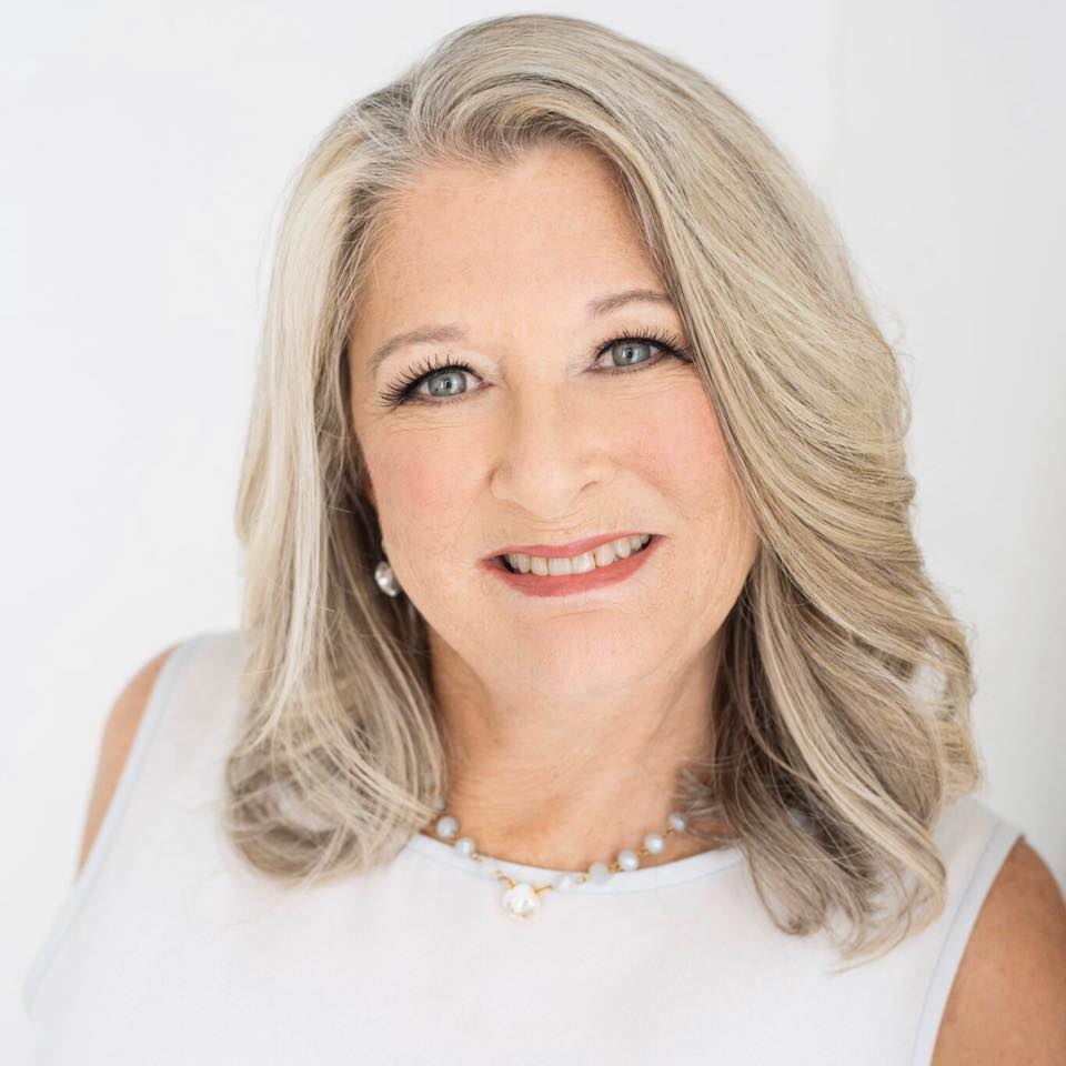 A Woman with open hair and white dress is smiling